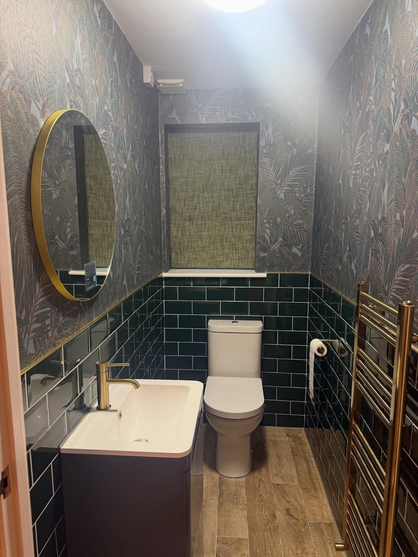 Green cloakroom with metro tiles, patterned walls and brushed-brass fittings