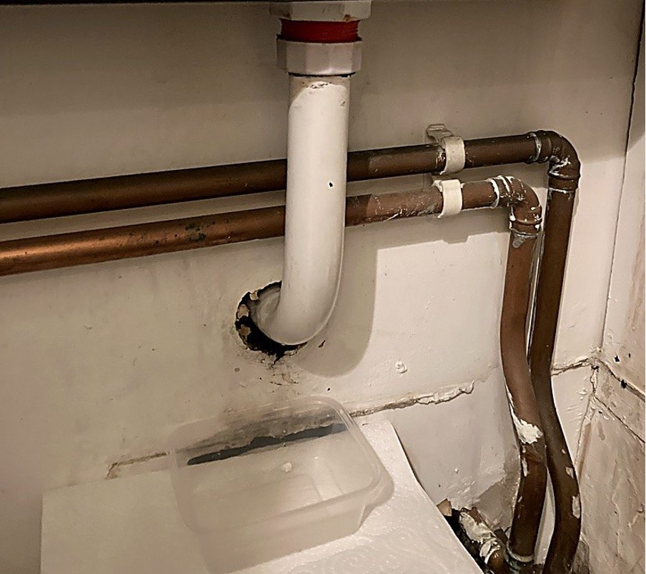 Leaking under-sink pipework caught in a tub before a repair