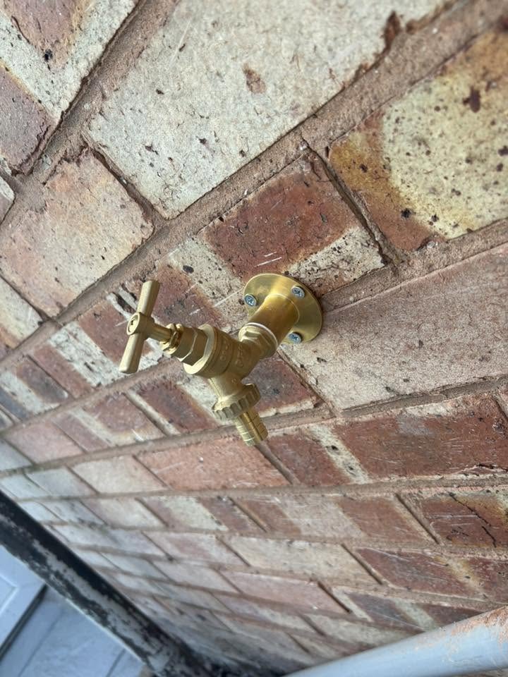 New brass outdoor garden tap with a cross-head handle, fitted to a brick wall