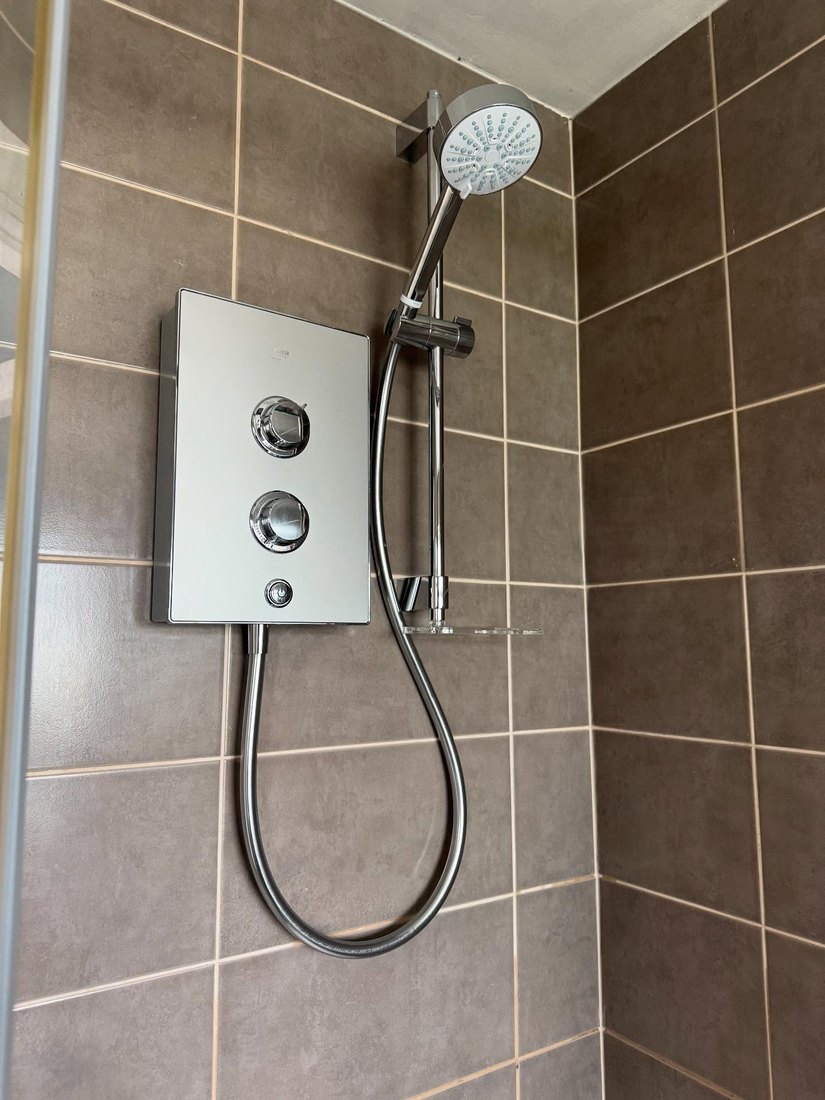 Mira electric shower fitted on brown tiles
